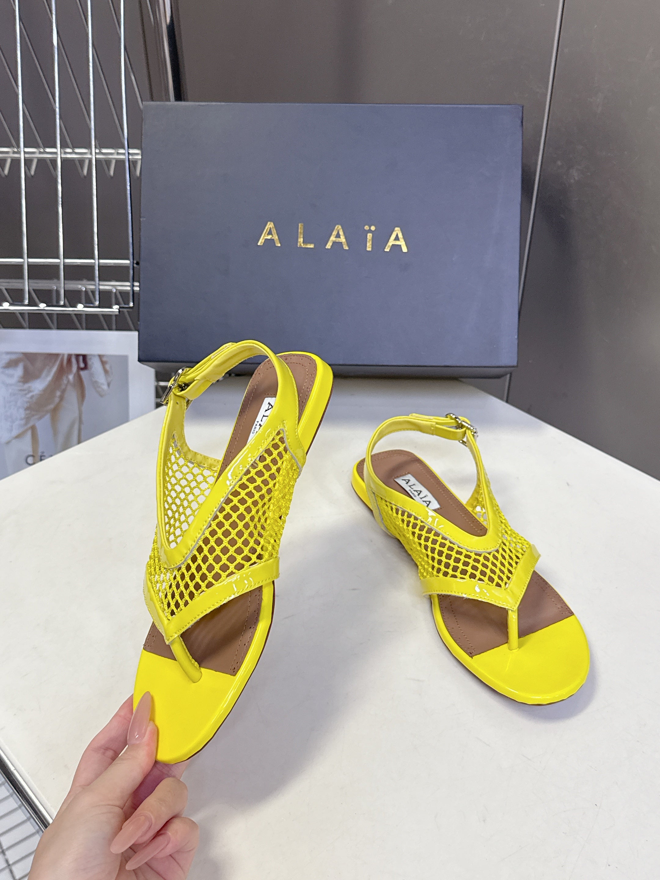 ALAIA 26S FLAT MESH THONG SANDALS IN YELLOW PATENT CALFSKIN