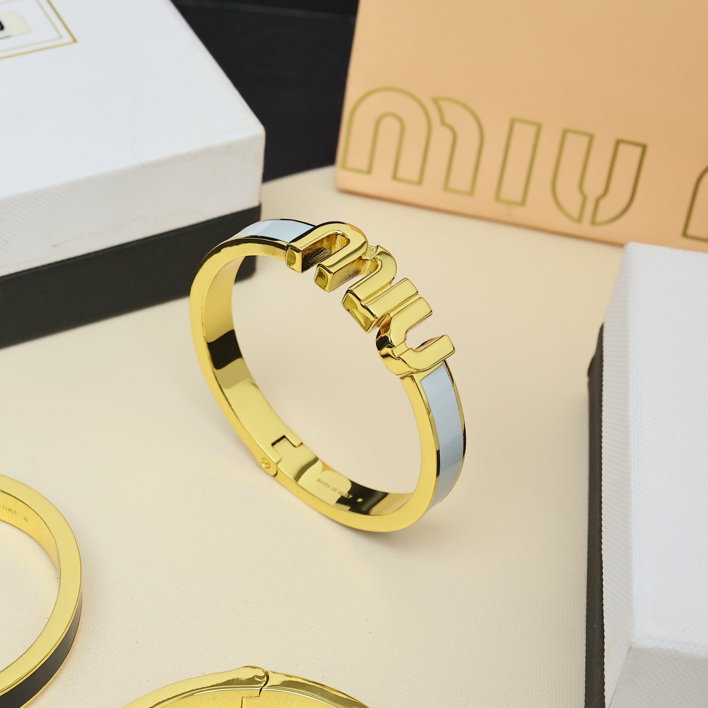 MIUMIU 26S LOGO HINGED BANGLE BRACELET WITH WHITE ENAMEL IN GOLD TONE METAL