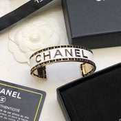 CHANEL 26S CHANEL LOGO ENAMEL CUFF BRACELET WITH BLACK TRIM IN GOLD METAL 630835